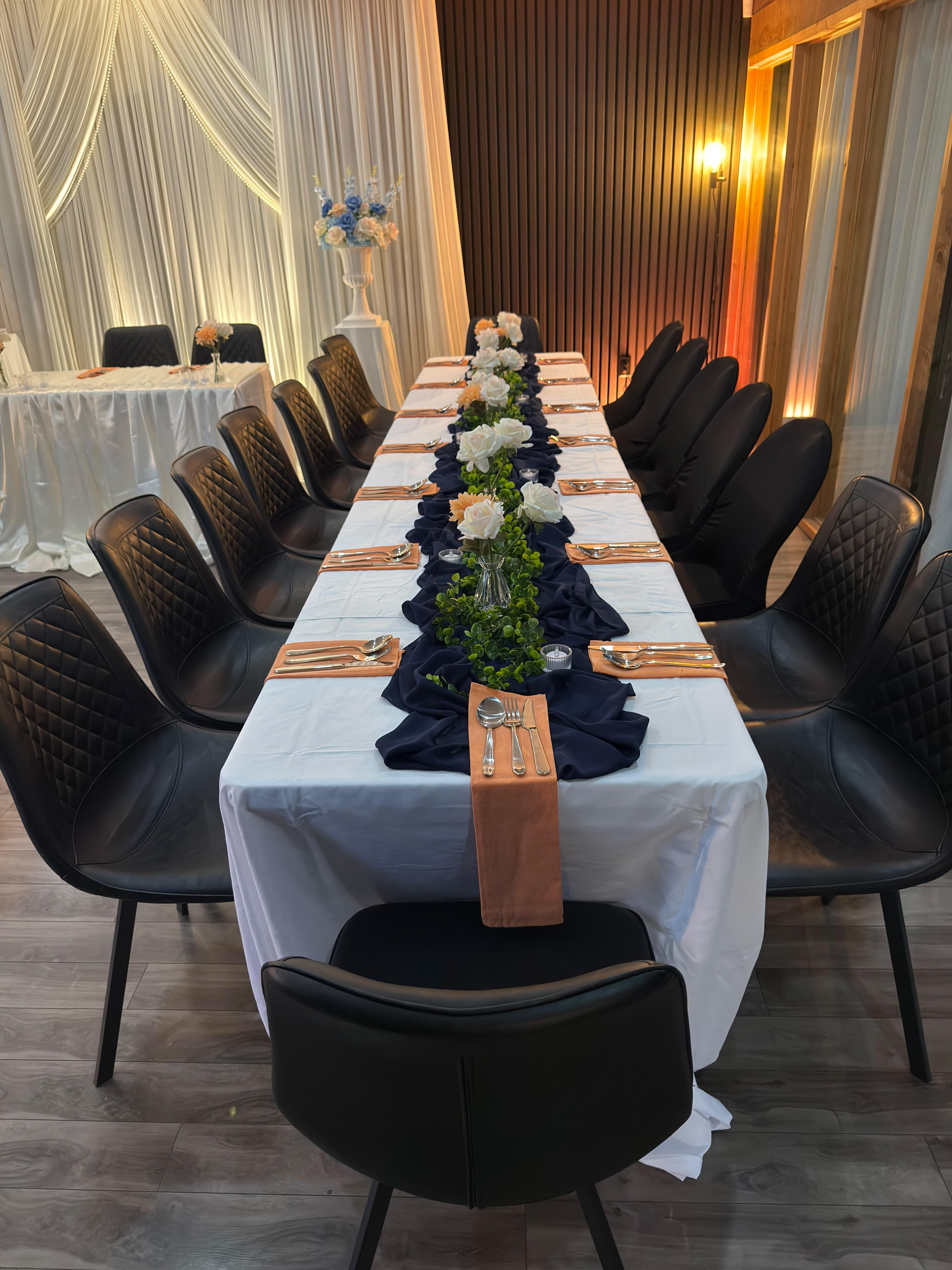 An intimate banquet table with flowers, greenery, and a draped wedding backdrop at KLAS Studio